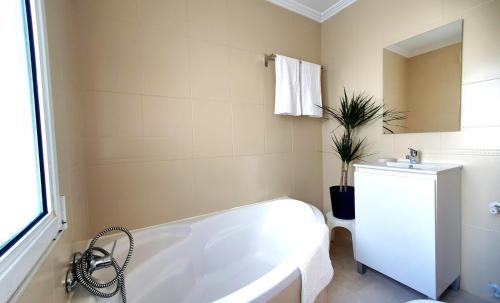 Baño blanco con bañera y lavamanos en La Luz de Acevedo en Oviedo