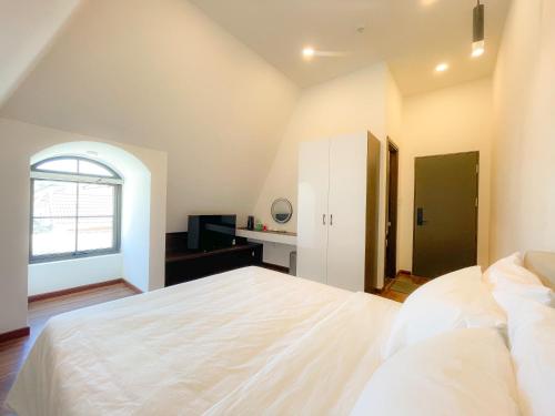 a bedroom with a large white bed and a window at Camellia Villa Hotel in Khu Chi Lăng