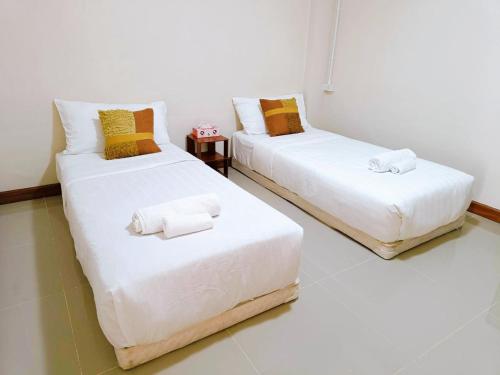 a room with two beds with towels on them at Baan PhakDeeChan in Chanthaburi