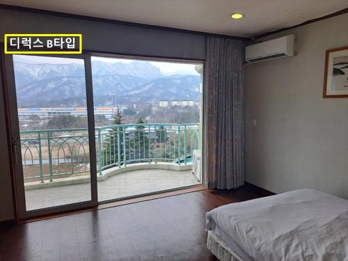a bedroom with a large window with a view of a balcony at Seorak Pine Resort in Sokcho
