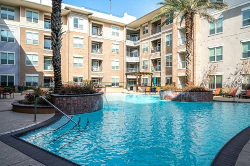a large swimming pool in a apartment complex with palm trees at PackHouse 2 in Houston