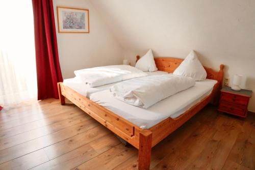 una camera da letto con letto in legno, lenzuola e cuscini bianchi di Gästehaus Wald und See a Titisee-Neustadt
