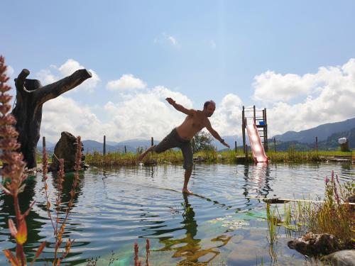 a man is jumping into a body of water at Bioferienhof Brückler in Laussa