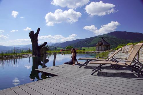 a woman sitting on a dock next to a body of water at Bioferienhof Brückler in Laussa