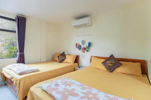 a bedroom with two beds and a window at Victor Charlie Hostel in Cat Ba