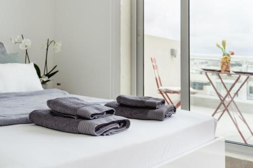 a pile of towels sitting on top of a bed at Stunning 1BDR Sliema-Center Penthouse! Near POOL! in Sliema