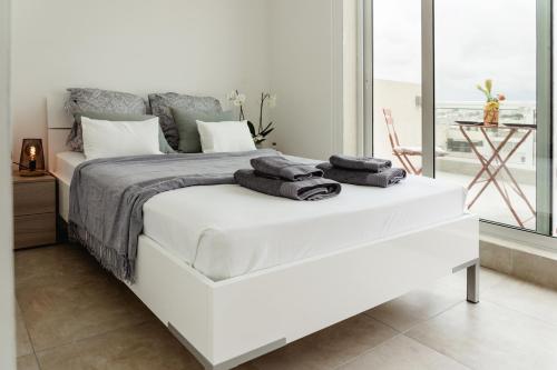 a bedroom with a white bed with towels on it at Stunning 1BDR Sliema-Center Penthouse! Near POOL! in Sliema