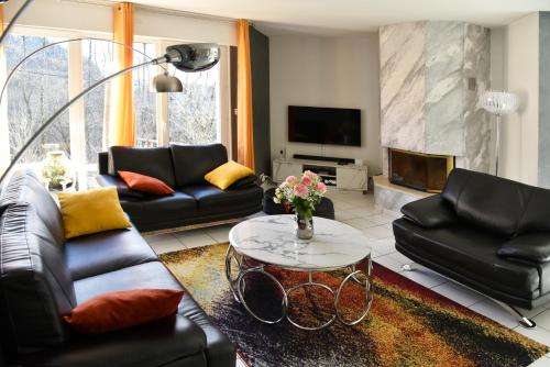 a living room with black leather furniture and a table at Villa Pré d'Oro 5 étoiles 10 personnes, spa privé, nature, Vosges Saônoises in Amage