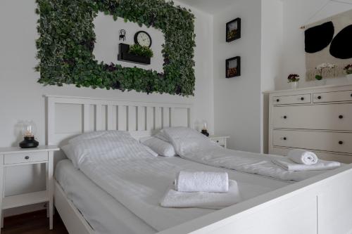 a white bedroom with a white bed with ivy on the wall at Zemplén Gyöngye Vendégház in Erdőhorváti