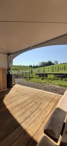 a tent with a wooden deck with a view of a field at Sheepinn de geul in Tielt