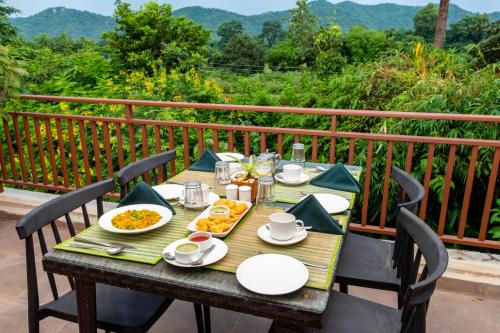 a wooden table with plates of food on a balcony at The Fern Sattva Resort - Polo Forest in Vijayanagar
