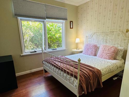 Schlafzimmer mit einem Bett mit rosa Kissen und einem Fenster in der Unterkunft Growse House 2BR in Yarram