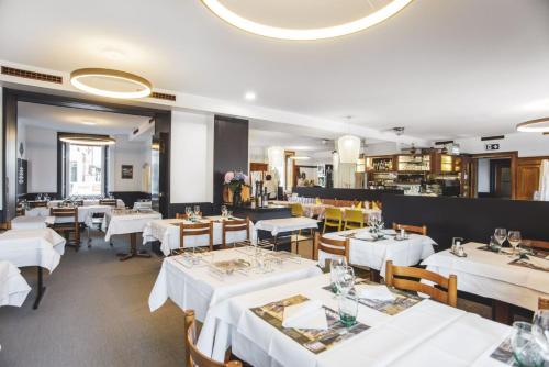 una sala da pranzo con tavoli e sedie bianchi di Hôtel Victoria a Delémont