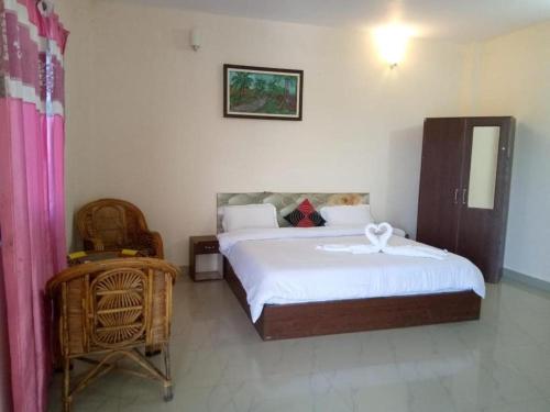 a bedroom with a large bed and a chair at CORBETT SUNRISE RESORT in Rāmnagar
