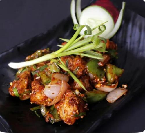 a black plate of food with shrimp and vegetables at The Kannelite in Jamshedpur