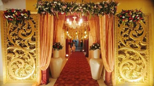 a corridor with curtains and a red carpet and a chandelier at The Kannelite in Jamshedpur