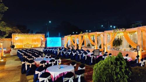a banquet hall with tables and chairs at night at The Kannelite in Jamshedpur