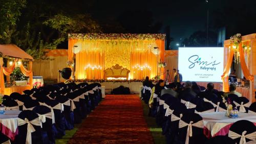 a banquet hall with tables and chairs and a screen at The Kannelite in Jamshedpur