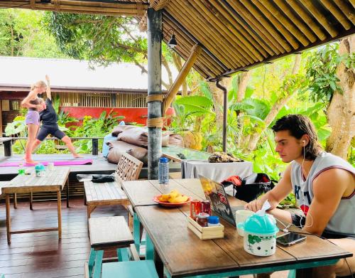ランタ島にあるAha Lanta Cozy Hostelの屋外パティオのテーブルに座る女性