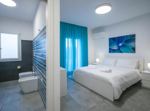 a bedroom with a white bed and a blue painting on the wall at Artemisia Home in Olbia