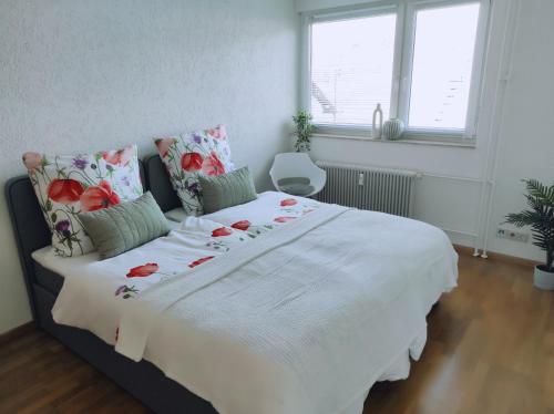 - une chambre avec un grand lit blanc orné de fleurs dans l'établissement Apartment Waldblick - 77 qm, 2 Schlafzimmer, Balkon und Wi-Fi, à Maulburg