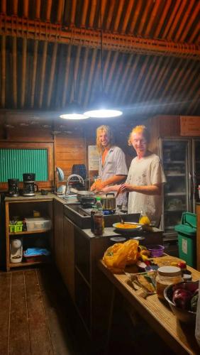 two people standing in a kitchen preparing food at Aha Lanta Cozy Hostel in Ko Lanta
