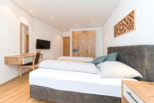 two beds in a hotel room with a desk and a television at Bel`Laret in Samnaun
