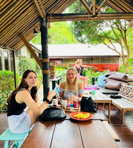 two women sitting at a table on a patio at Aha Lanta Cozy Hostel in Ko Lanta