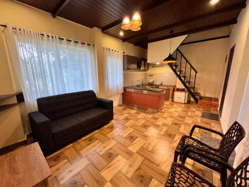 a living room with a black couch and a wooden floor at Zyamadhari in Mananthavady