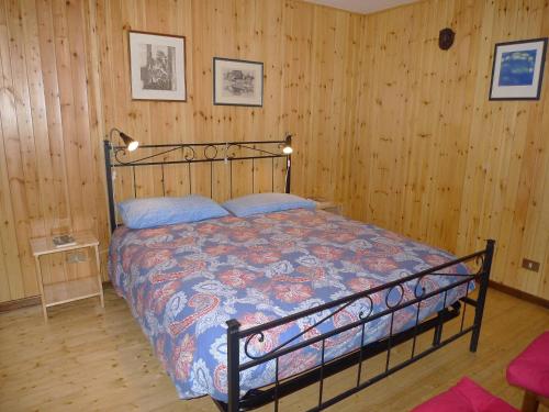 a bedroom with a bed in a room with wooden walls at Maison al Lago in Alleghe