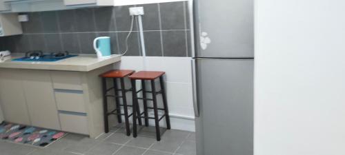 a kitchen with a refrigerator and two bar stools at Kerian Putra Muslimstay in Parit Buntar