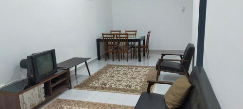 een woonkamer met een tv en een tafel en stoelen bij Kerian Putra Muslimstay in Parit Buntar