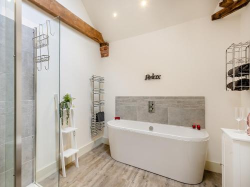 La salle de bains est pourvue d'une baignoire blanche et d'une douche. dans l'établissement Archies Barn, à Lenwade