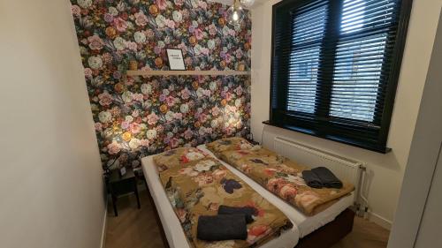 Habitación pequeña con cama y pared de flores. en Heiligeweg 48, en Harlingen