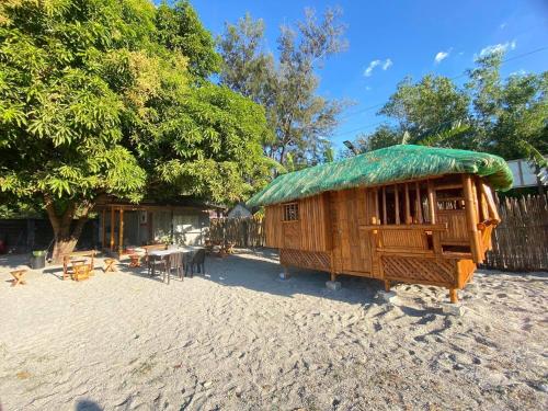 Cabaña pequeña con techo verde en una playa en Camp Binoclutan Kubotel en Botolan