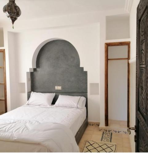 Tanazart guest house في تارودانت: غرفة نوم مع سرير كبير مع اللوح الأمامي رمادي