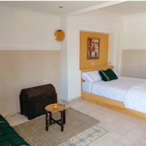 1 dormitorio con 2 camas, mesa y taburete en Tanazart guest house, en Taroudant