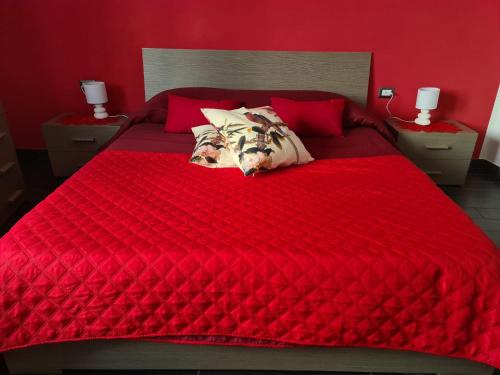 un letto rosso con lenzuola rosse e cuscini sopra di Affittacamere Sa Pardula a Cagliari