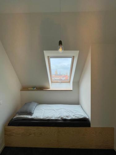 een klein bed in een kamer met een raam bij Julie's appartement aan zee - JAAZ in Nieuwpoort