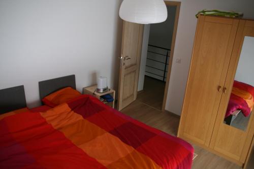 a bedroom with a bed with a colorful blanket at Entre Sève Et Ciel in Tillet