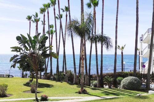 uma fila de palmeiras num parque junto ao oceano em ALGAIDA BEACHFRONT - Seaview Costa del sol em Sitio de Calahonda