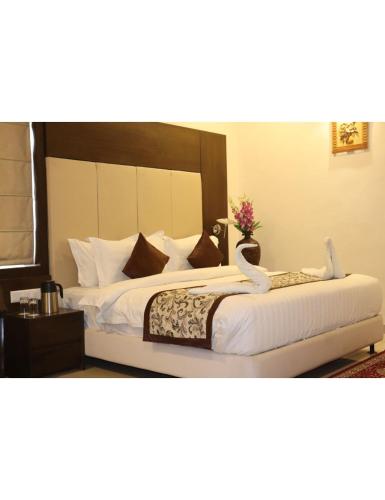 um quarto com 2 camas e lençóis brancos em Hotel Solista, Chittorgarh-312001, em Chittaurgarh