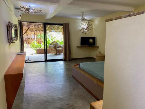 1 dormitorio con 1 cama y sala de estar con TV. en La perle rare de Nosy be en Ambatoloaka