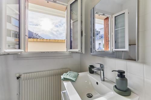 une salle de bain avec un lavabo et deux miroirs dans l'établissement Le Kennedy, à Trouville-sur-Mer