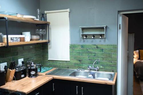 a kitchen with a sink and a green tiled wall at Comfortable 2-Bedroom place with indoor Fireplace in Mossel Bay