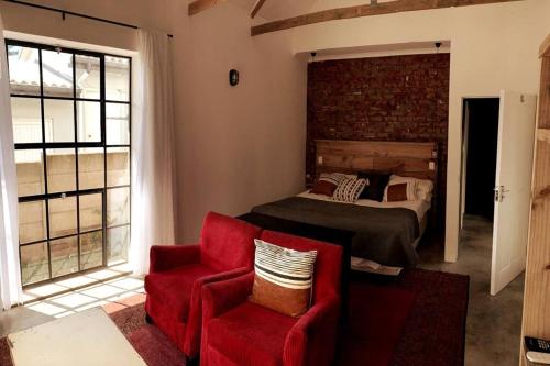 a bedroom with a bed and a red chair at Comfortable 2-Bedroom place with indoor Fireplace in Mossel Bay