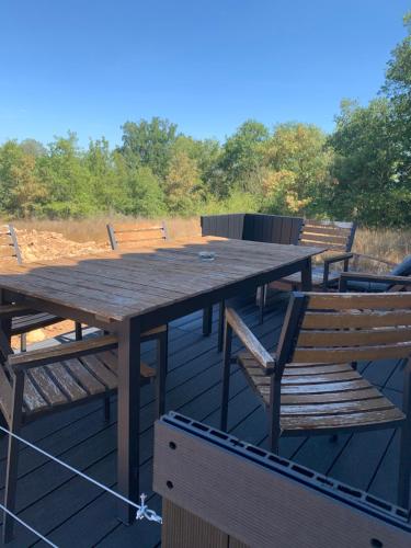 - une table de pique-nique en bois et des chaises sur une terrasse dans l'établissement Studio meublé, à Les Plans