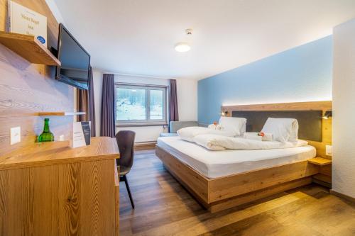 um quarto de hotel com uma cama e uma televisão em Hotel Kristall-Saphir Superior em Saas-Almagell