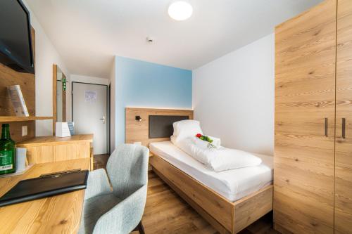 a room with a bed with a desk and a chair at Hotel Kristall-Saphir Superior in Saas-Almagell