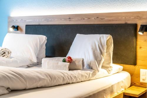 a bed with white pillows and a red flower on it at Hotel Kristall-Saphir Superior in Saas-Almagell